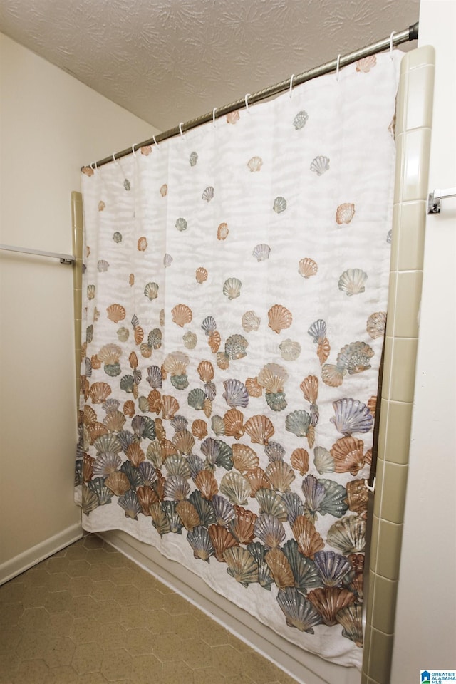 full bathroom featuring curtained shower and a textured ceiling