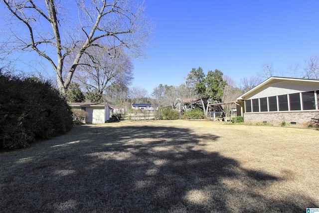 view of yard featuring a storage unit, an outdoor structure, fence, and a sunroom