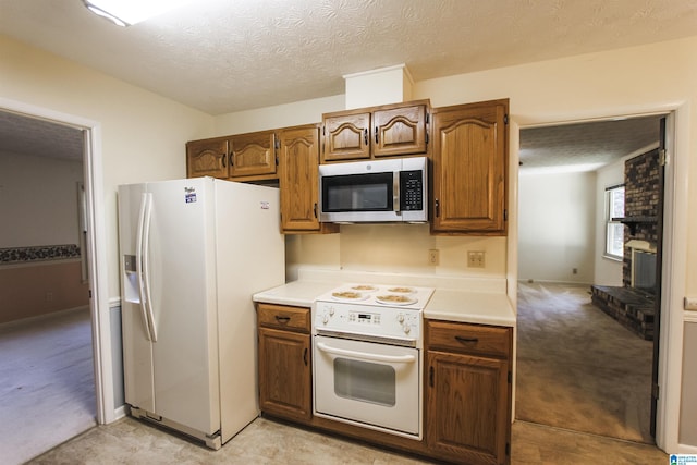 kitchen with light countertops, white appliances, light carpet, and a textured ceiling