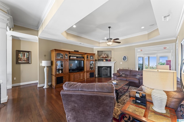 living room featuring visible vents, a raised ceiling, baseboards, wood-type flooring, and a fireplace