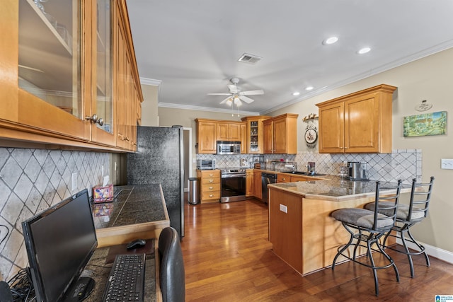 kitchen featuring dark wood-style floors, a breakfast bar, stainless steel appliances, brown cabinetry, and a peninsula