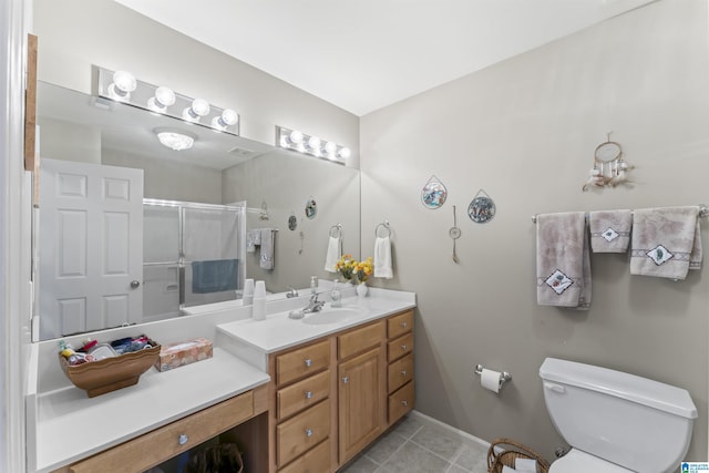 bathroom featuring a shower with door, toilet, vanity, baseboards, and tile patterned floors