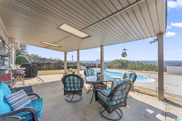 view of patio with fence, a grill, and an outdoor pool