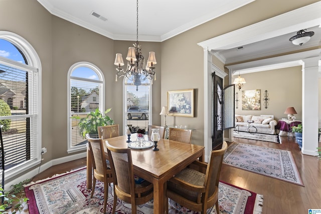 dining space featuring ornamental molding, wood finished floors, visible vents, and an inviting chandelier