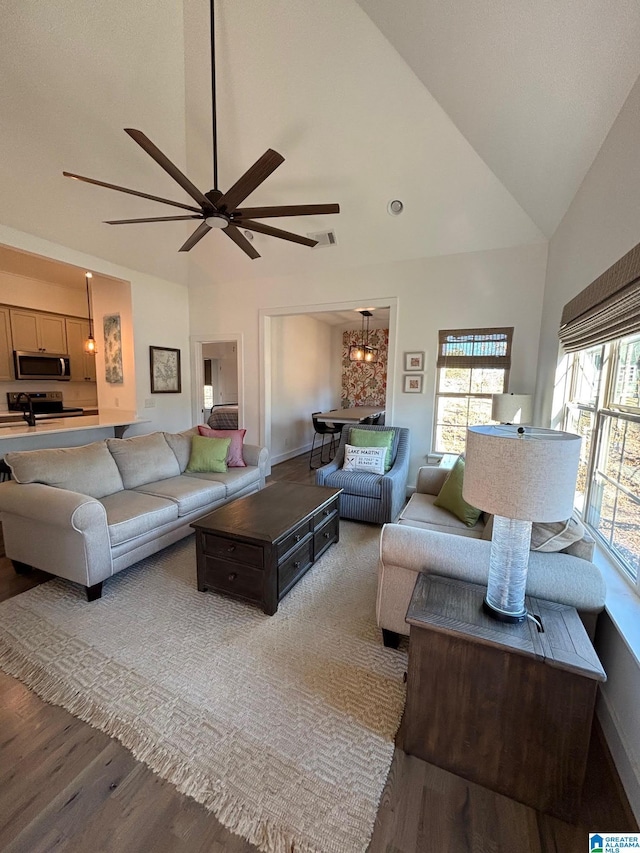 living room featuring a ceiling fan, visible vents, baseboards, and wood finished floors