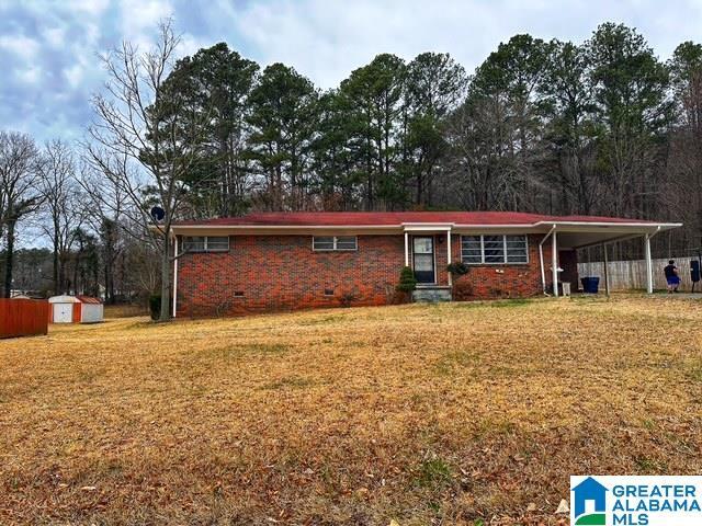 ranch-style home featuring brick siding, a storage unit, crawl space, an outdoor structure, and a front lawn