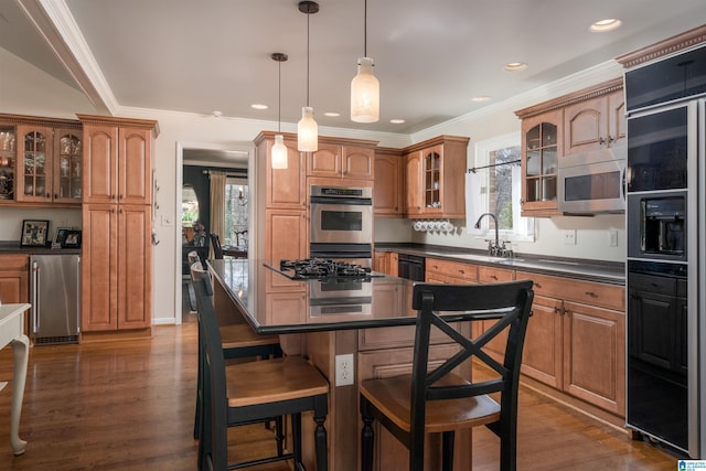 kitchen with dark wood-style flooring, dark countertops, a sink, black appliances, and a kitchen bar