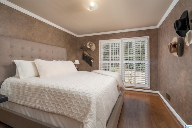 bedroom featuring ornamental molding, wood finished floors, visible vents, and baseboards