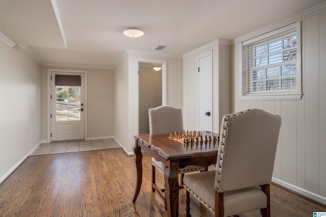 dining area featuring light wood finished floors, baseboards, visible vents, and ornamental molding