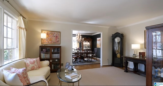 living area with ornamental molding, a chandelier, baseboards, and wood finished floors