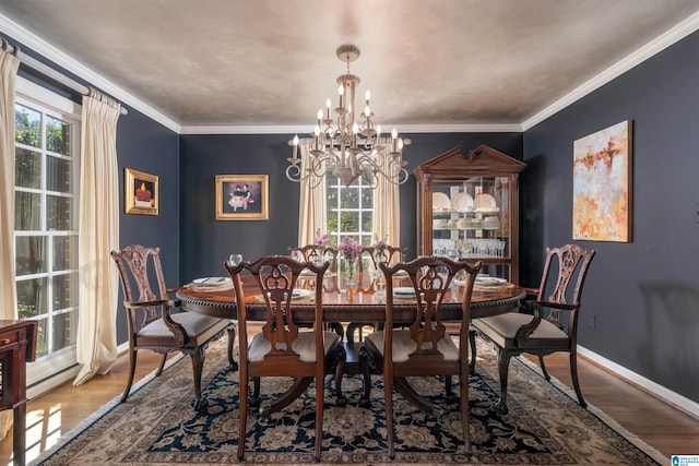 dining space with a notable chandelier, ornamental molding, wood finished floors, and baseboards