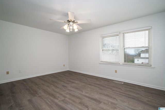 spare room featuring visible vents, dark wood finished floors, and baseboards