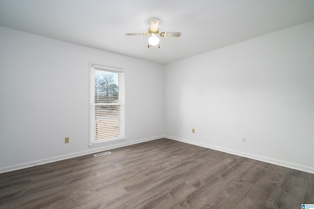 spare room with visible vents, dark wood finished floors, baseboards, and ceiling fan