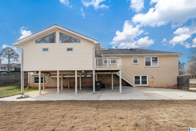 back of property featuring brick siding, a patio, a wooden deck, and fence