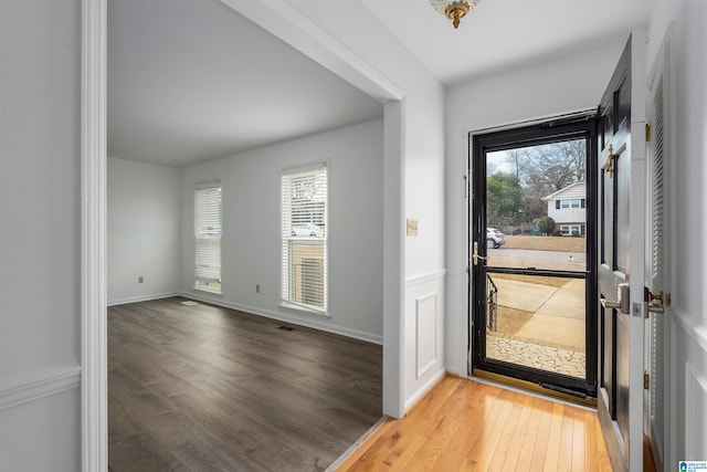 foyer featuring light wood-style floors, plenty of natural light, visible vents, and baseboards