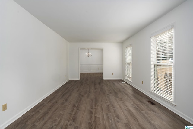 interior space featuring dark wood-style floors, baseboards, visible vents, and an inviting chandelier