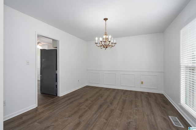 unfurnished room with a notable chandelier, visible vents, a decorative wall, and dark wood-style flooring