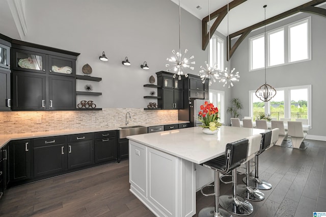 kitchen featuring a sink, backsplash, open shelves, dark wood finished floors, and an inviting chandelier