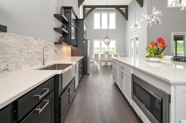 kitchen with hanging light fixtures, an inviting chandelier, stainless steel appliances, light countertops, and open shelves