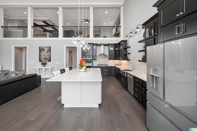 kitchen featuring white refrigerator with ice dispenser, a sink, light countertops, wall chimney exhaust hood, and tasteful backsplash