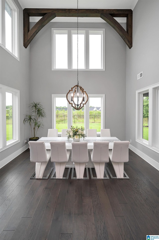 dining area featuring a notable chandelier, dark wood-type flooring, a towering ceiling, baseboards, and visible vents