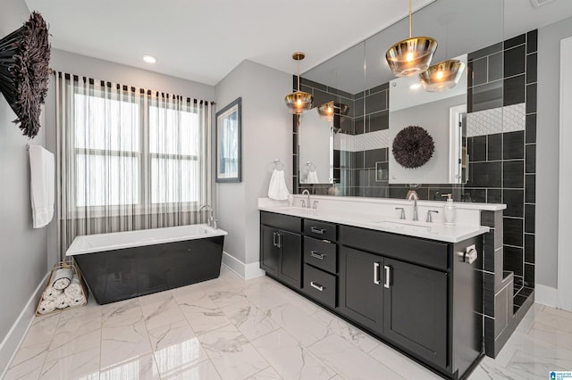 bathroom with marble finish floor, double vanity, a soaking tub, a sink, and baseboards