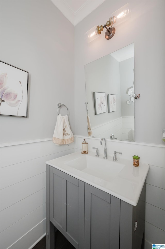 bathroom with a wainscoted wall, crown molding, and vanity