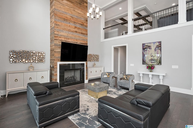 living room with baseboards, wood-type flooring, a high ceiling, a fireplace, and a notable chandelier