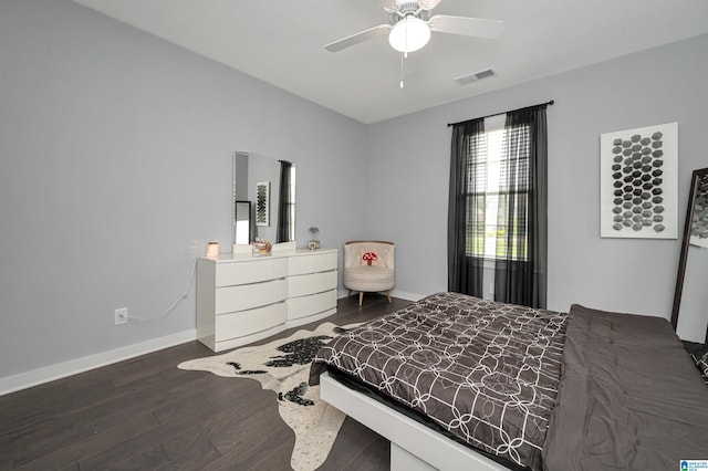 bedroom with a ceiling fan, visible vents, baseboards, and wood finished floors