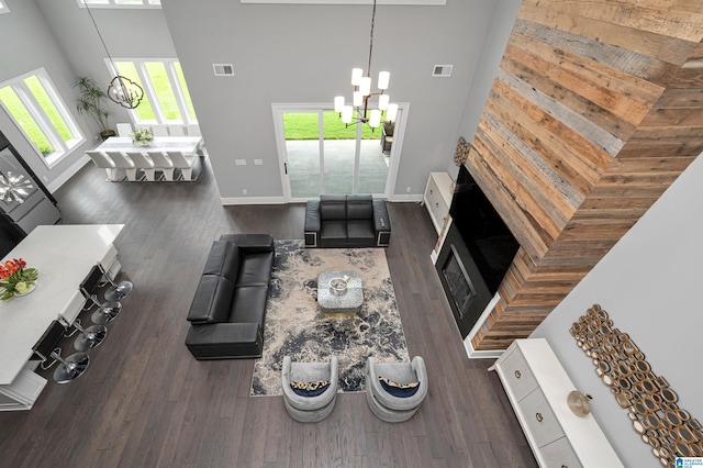 living area featuring visible vents, wood finished floors, a towering ceiling, and an inviting chandelier