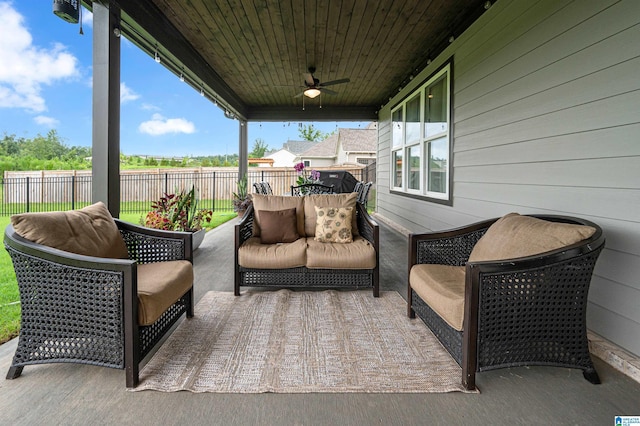 wooden terrace with an outdoor hangout area, a patio, fence, and a ceiling fan