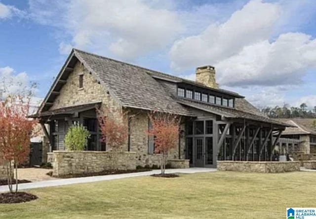 rear view of property with a sunroom, a chimney, stone siding, and a lawn