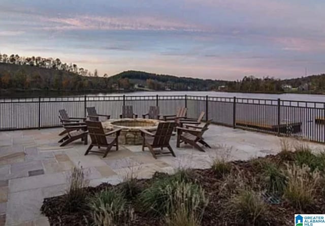 view of patio featuring a water view, fence, and a fire pit