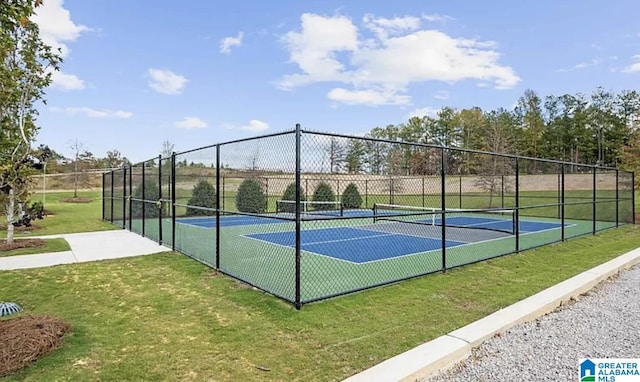 view of tennis court with fence and a lawn