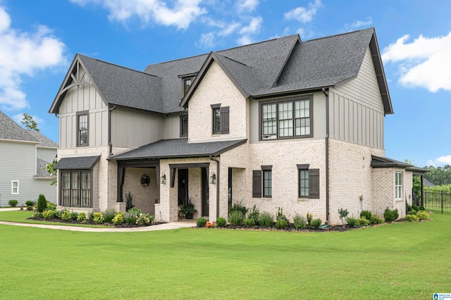 modern farmhouse style home with roof with shingles, a front lawn, board and batten siding, and brick siding