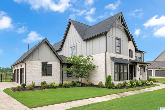 modern farmhouse with a garage, brick siding, concrete driveway, a front lawn, and board and batten siding