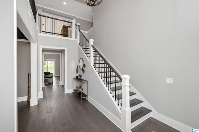 staircase featuring recessed lighting, wood finished floors, a towering ceiling, and baseboards