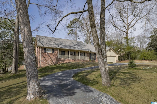 view of front facade with a porch, brick siding, driveway, and a front lawn