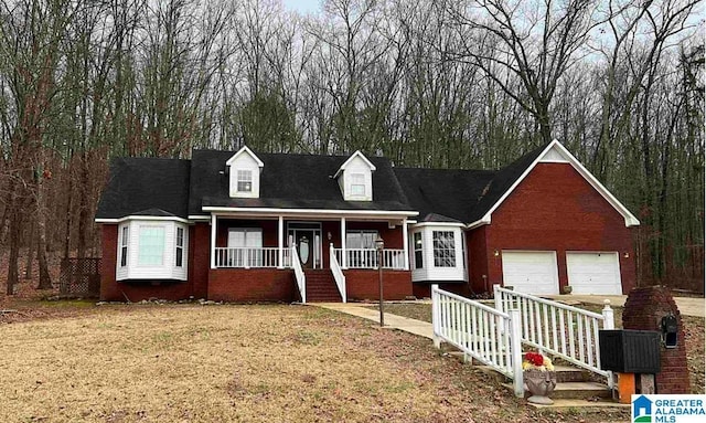 cape cod home featuring covered porch, a garage, brick siding, driveway, and a front lawn