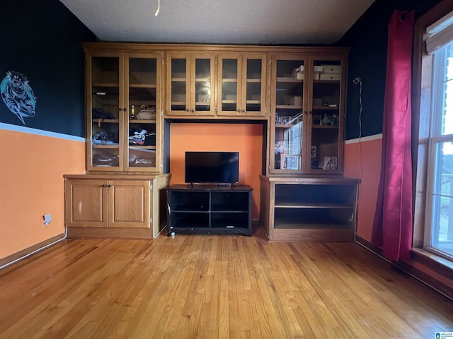 unfurnished living room with a textured ceiling and wood finished floors