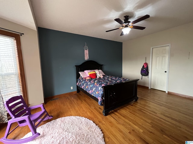 bedroom with ceiling fan, baseboards, and wood finished floors