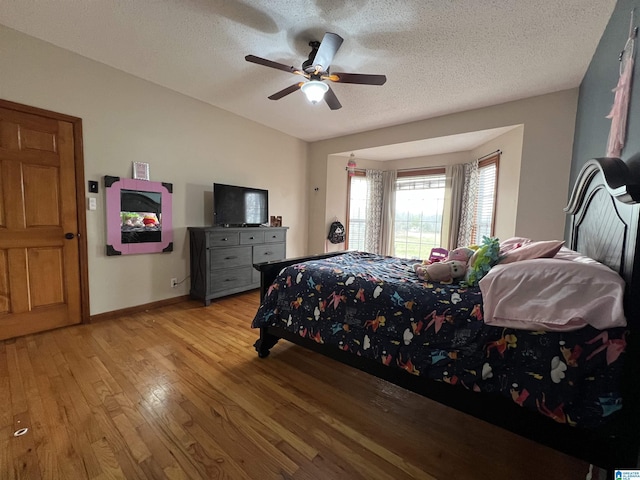 bedroom featuring baseboards, a textured ceiling, a ceiling fan, and light wood-style floors