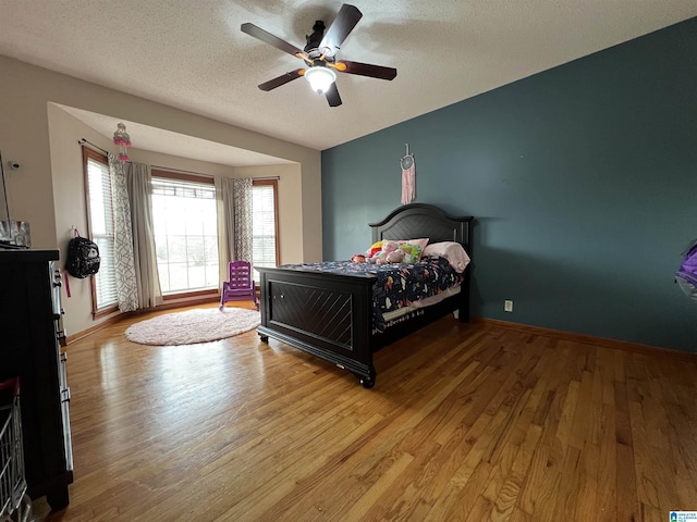 bedroom with a textured ceiling, baseboards, and wood finished floors