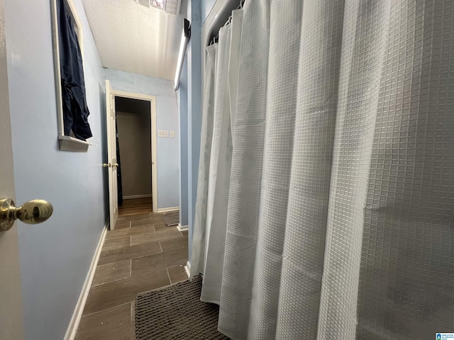 corridor with baseboards and wood finish floors