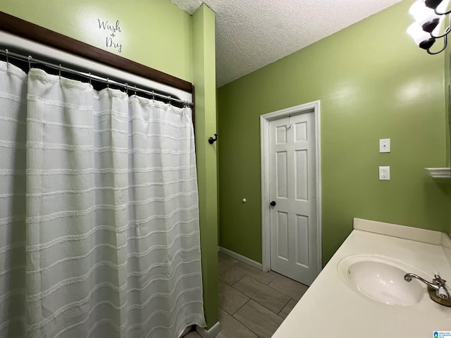 full bath with curtained shower, a textured ceiling, and vanity