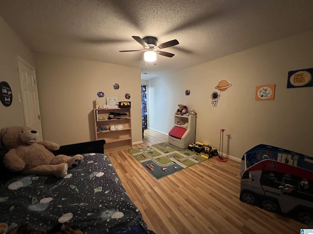 bedroom with ceiling fan, a textured ceiling, baseboards, and wood finished floors