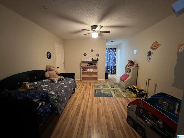 bedroom with a textured ceiling, ceiling fan, baseboards, and light wood-style floors