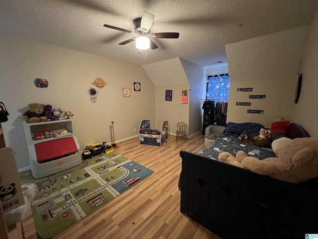 bedroom with lofted ceiling, light wood-style floors, a ceiling fan, a textured ceiling, and baseboards