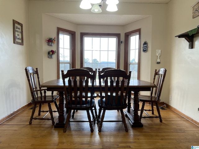 dining room with an inviting chandelier, baseboards, and wood finished floors