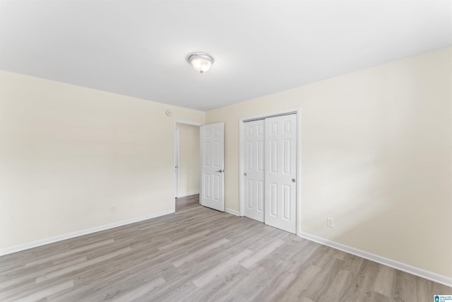 unfurnished bedroom featuring light wood finished floors, a closet, and baseboards